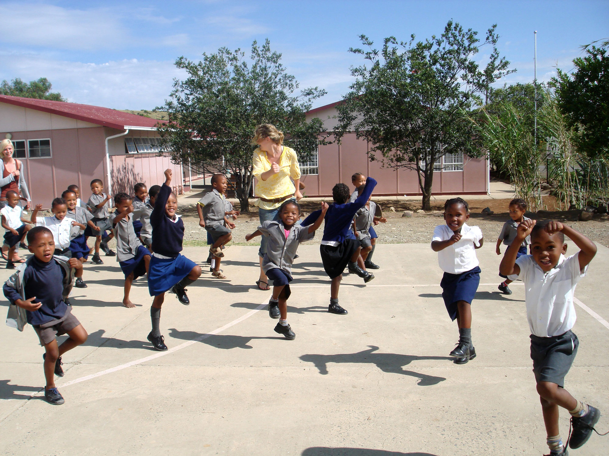 Volunteer and children jumping in the playground